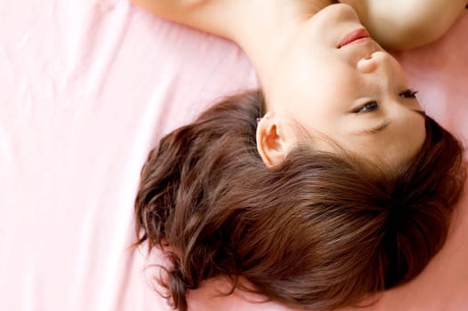 A beautiful young woman laying in bed and smiling