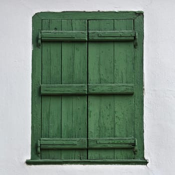 Green wooden window shutter and white wall.