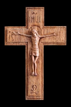 Wooden crucifix with skull and crossbones isolated on black background.