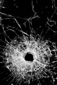 broken glass isolated on black - authentic bullet hole - close up