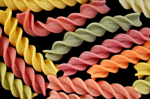 Multi colored fusilli italian pasta on black background. Creative food.