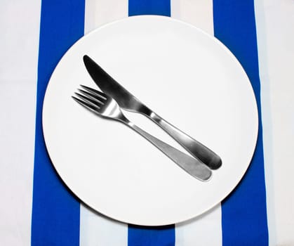Empty Plate And Silverware on tablecloth in greek colors