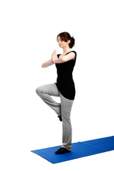 Young woman exercising yoga on one leg and pressing palms together
