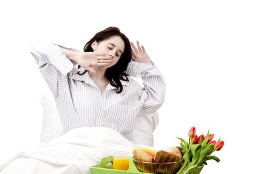 Young woman yawning at breakfast in bed