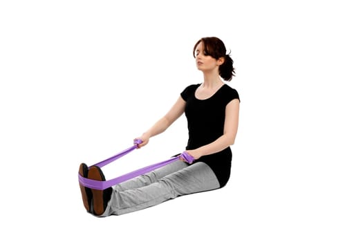 Young pretty woman sitting on the floor exercising with an exercise band