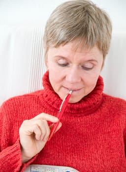 Head and shoulders portrait of a mature woman in a red sweater,puzzle book and pen