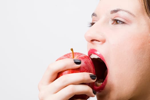 a young pretty girl eating a fresh healthy red apple
