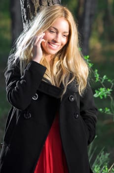 a young beautiful real girl talking with her mobile phone in the nature