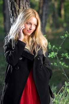 a young beautiful real girl talking with her mobile phone in the nature