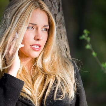 a young beautiful real girl talking with her mobile phone in the nature
