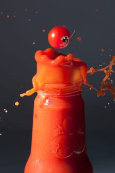 Tomatoes fall into a bottle of tomato juice
