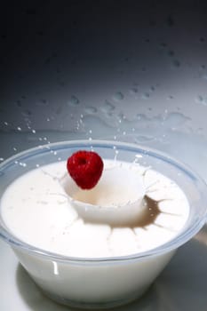 Raspberries fall into milk