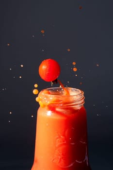 Tomatoes fall into a bottle of tomato juice