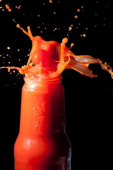 Tomatoes fall into a bottle of tomato juice
