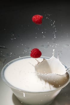 Raspberries fall into milk