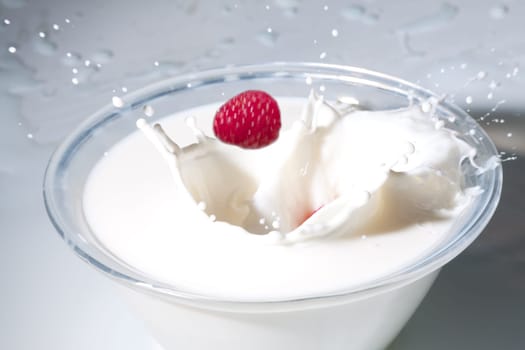 Raspberry falls into a bowl of milk