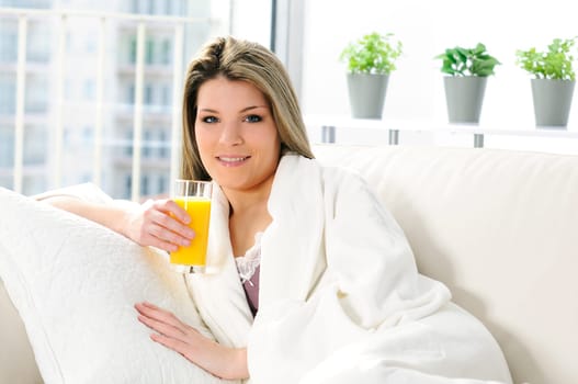 Beautiful blond woman relaxing at home whith an orange juice