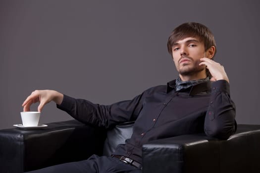 fashion man sitting in chair with cup coffee