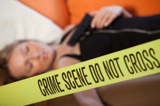 crime scene - dead woman with gun. Focus on boundary tape