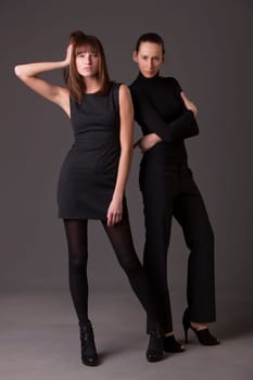 two fashion women in black dresses and high heels showing new collection