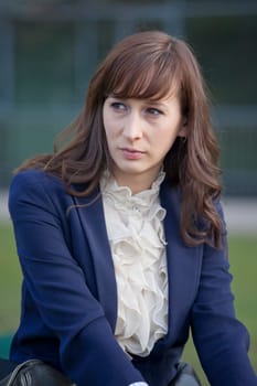 portrait of sad woman in elegant jacket sitting outdoor