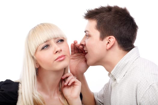 Portrait of a  young man whispering a secret to a cute woman against white