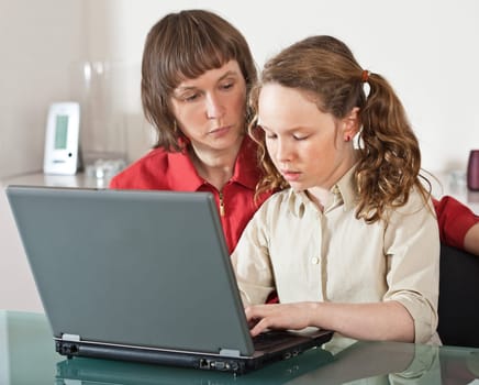 Mother and teenager girl with laptop computer together at home