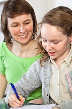 Teenager girl sitting together with her mother and showing her homework