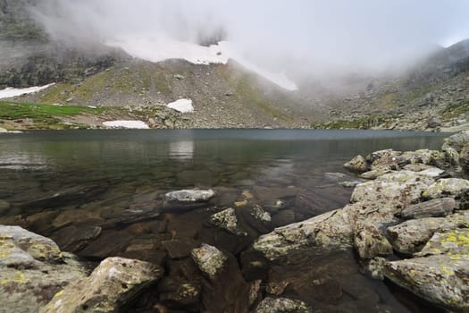 snow and fog near a mountain lake