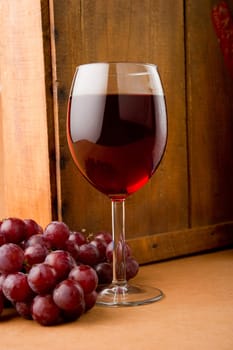 Image of a glass of wine and grapes next to old wooden box