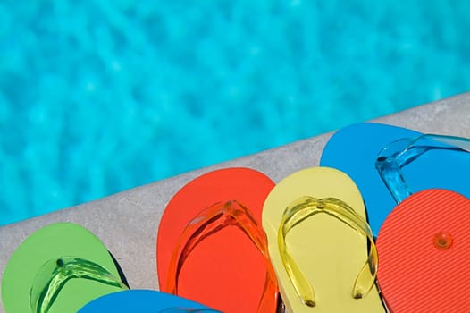 Colored flipflops of a family of four by the swimming pool
