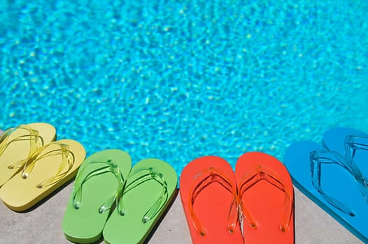 Colored flipflops of a family of four by the swimming pool