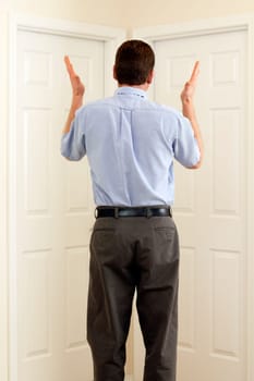 Man between two doors with hands in the air not sure which to choose.