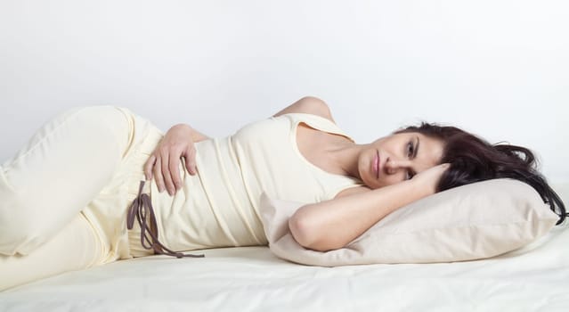 Pretty young brunette woman lying in bed