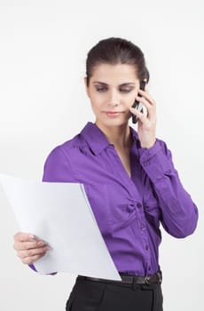 Pretty young businesswoman holding the papers and talking on cellphone