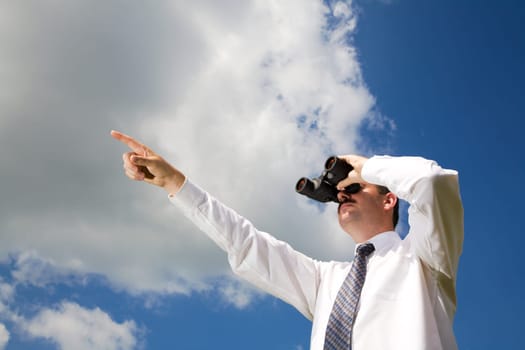 Businessman is looking ahead through binoculars with sky in the background