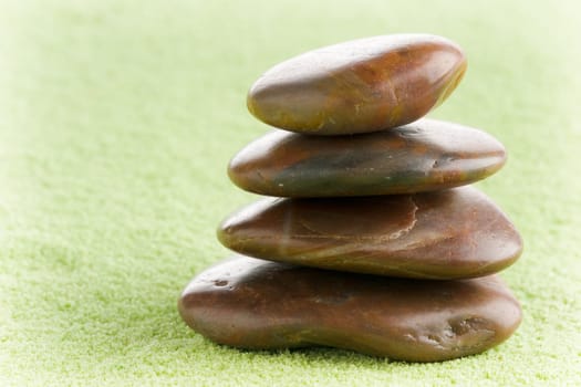 Brown flat stones in balance on green sand