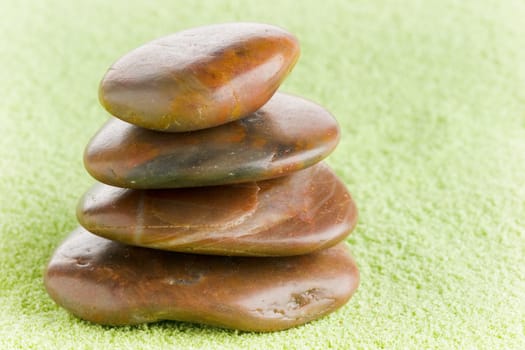 Brown flat stones in balance on green sand
