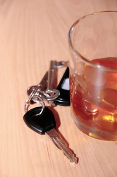 whiskey glass and keys on office desk depicting drinking and driving at work