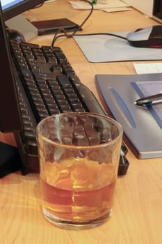 whiskey glass on office desk depicting drinking at work