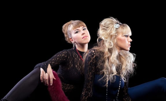 Two pretty sisters posing in lace costume in dark