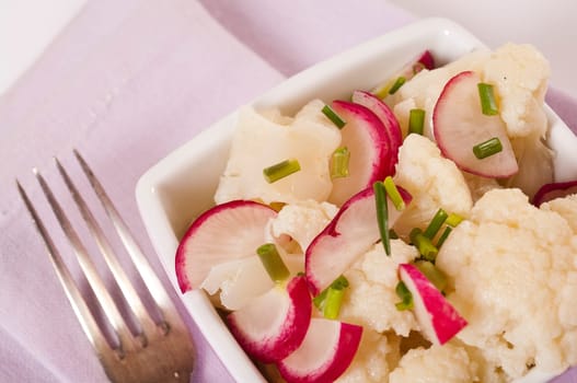 Cauliflower salad with radishes in pink bowl