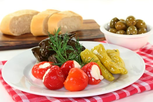 Stuffed pepperoni,vine leaves and green olives against a white background