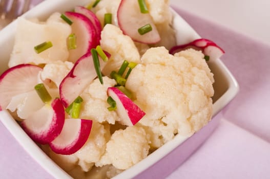 Cauliflower salad with radishes in pink bowl