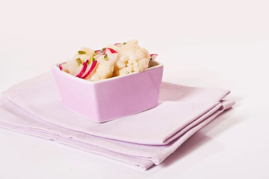 Cauliflower salad with radishes in pink bowl