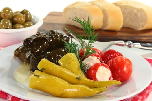 Stuffed pepperoni,vine leaves and green olives against a white background