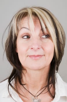 Head portrait of a mature blonde woman with dark streaks looking to the side with only her eyes