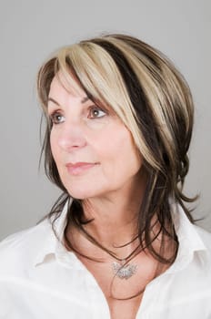 Head portrait of a mature blonde woman with dark streaks looking to the side with head and eyes