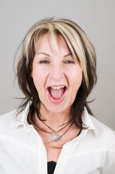 Head portrait of a mature blonde woman with dark streaks looking at the camera with her mouth open and head-on