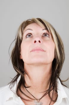 Head portrait of a mature blonde woman with dark streaks looking up with only her eyes
